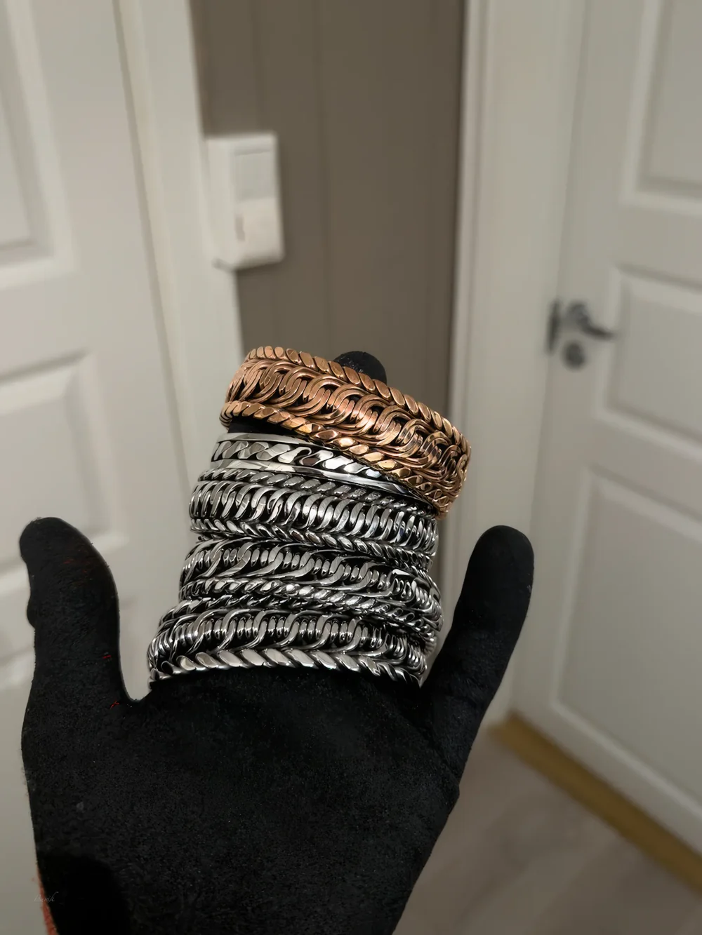 Håndflettede armbånd i polert rustfritt stål og kobber.